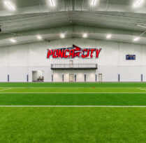 Close up of turf field with Ponca City emblem on wall