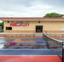 Middle of tennis courts with facility behind it