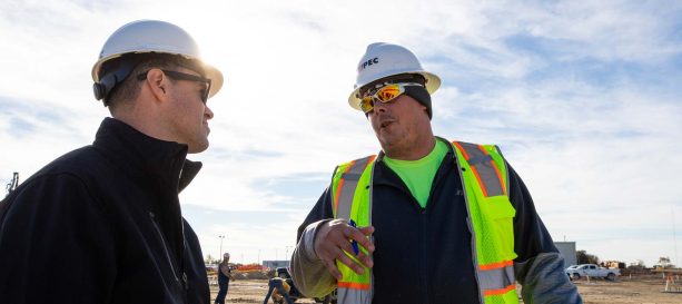 A client and manager outside on a job site in safety gear