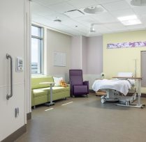 Large hospital room suite with bed, couches, and bathroom