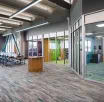Aisle of library with conference room on one side and row of computers