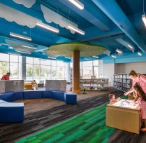 Children's library area with long blue couch and clouds on ceiling