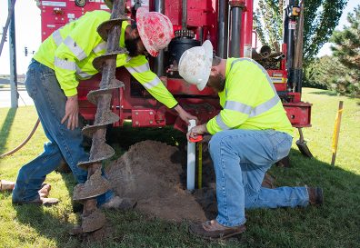 Two field service workers with large drill