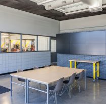 Front entrance with tables, chairs, and tv screens on brick wall
