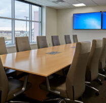 Conference room with large table, chairs, and tv screens